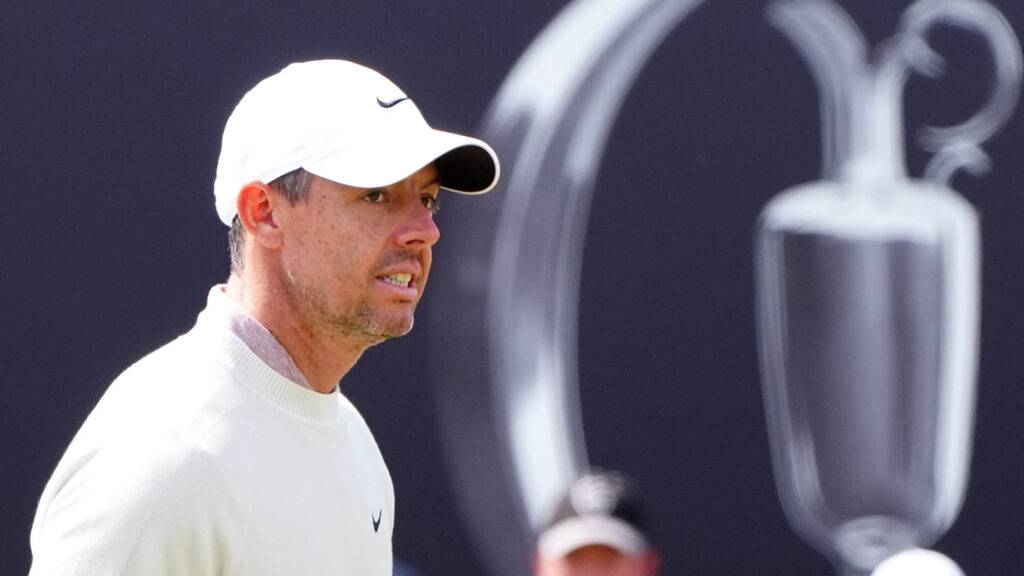 Rory McIlroy walks beside an image of the Claret Jug