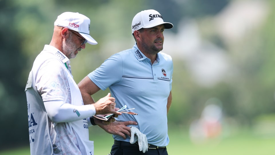 Keegan Bradley talks with his caddie on the second hole during the first round 