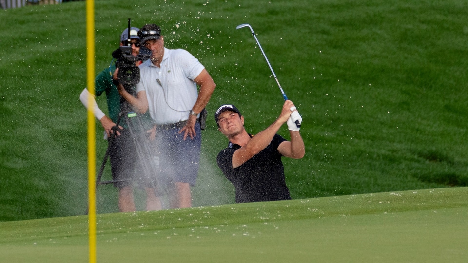 Viktor Hovland hits out of the bunker on the 18th hole during the first round