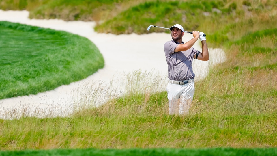 Scottie Scheffler plays a shot on the fourth hole out of the church pew bunker during the first round