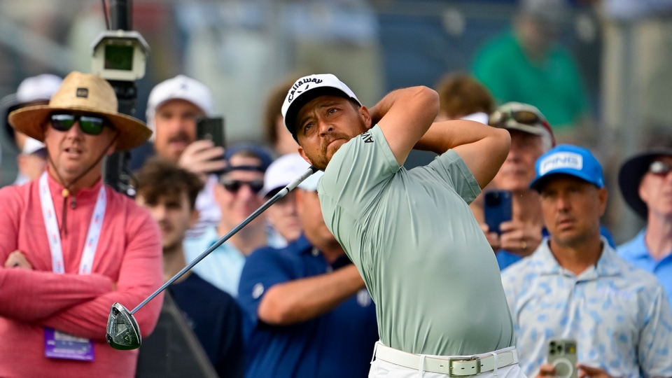 Xander Schauffele plays his shot on the 12th hole as the crowd looks on during a practice round